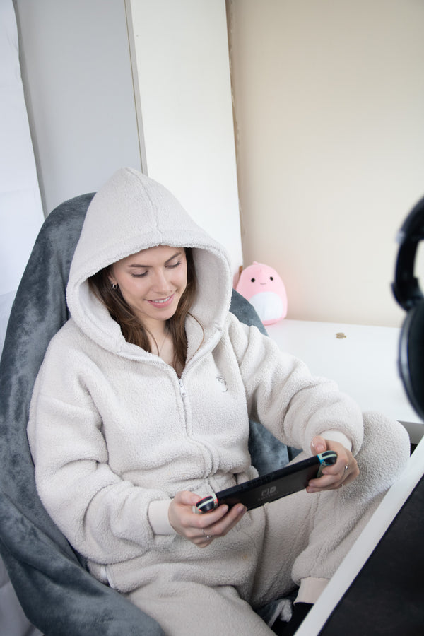 Gamer sat wearing the becosy ultimate sherpa onesie in stone playing on a nintendo switch
