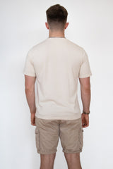 A back view of a male model wearing a cream cosycore by beCosy short sleeve tshirt with an embroidered cat logo
