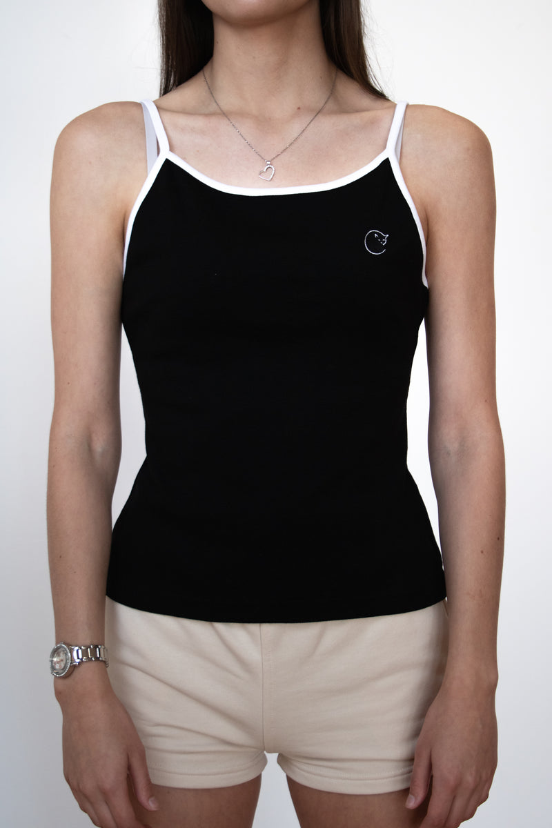 close up front view of female model wearing a black cosycore tank top with embroidered cat logo showing off the figure flattering fit