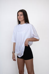 Side view of female model wearing a white cosycore by becosy oversized womens tshirt with embroidered logo