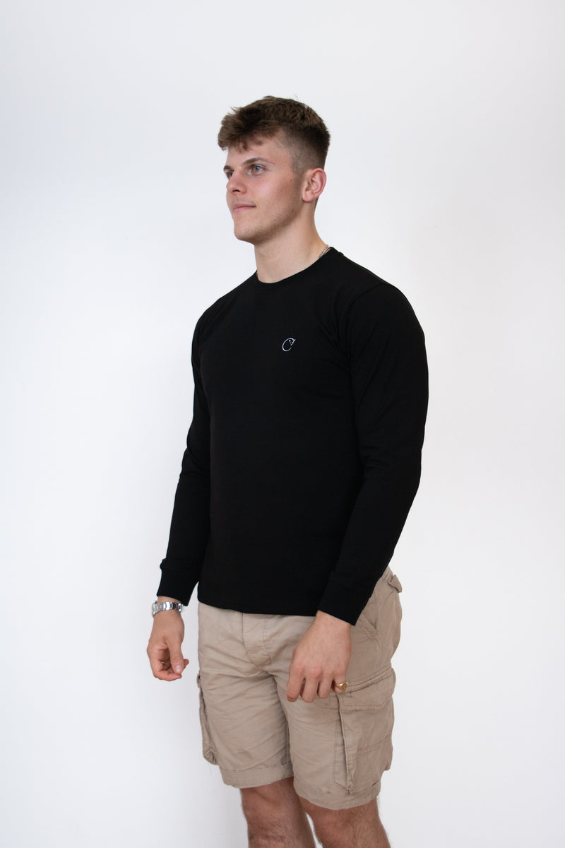 Side view of a male model wearing a black long sleeve cosycore tshirt by beCosy with an embroidered cat logo