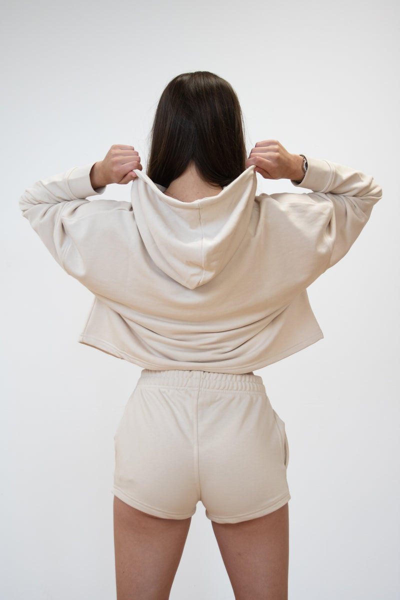 back view of female model showing of the cosycore cream terry shorts from beCosy matched with the cosycore cropped hoodie